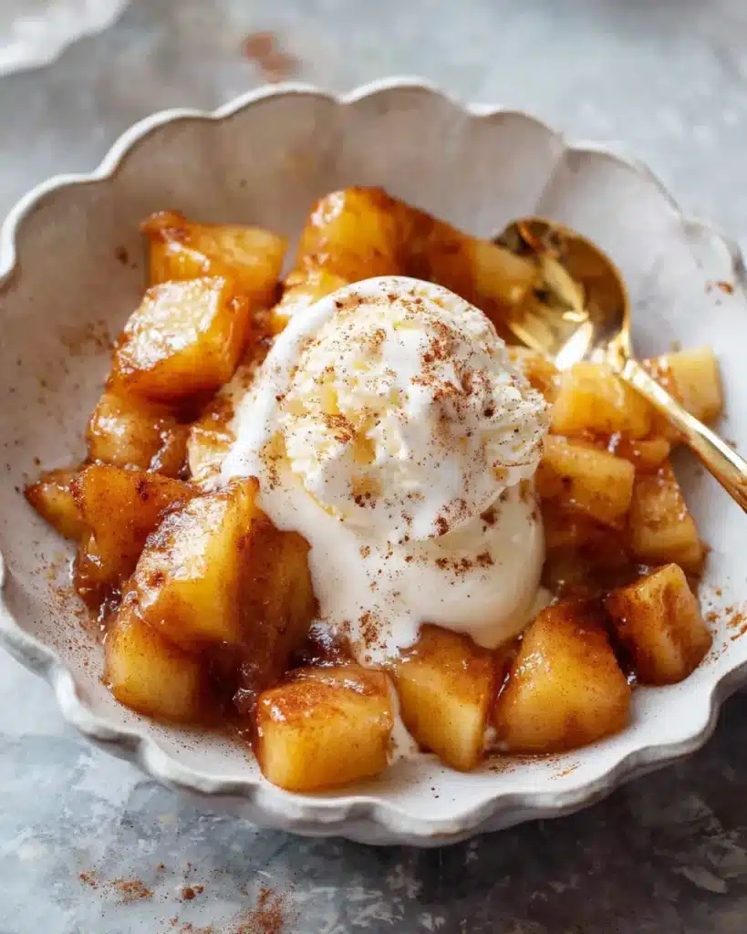 Caramelized cinnamon air fryer apples with melting vanilla ice cream in a white bowl