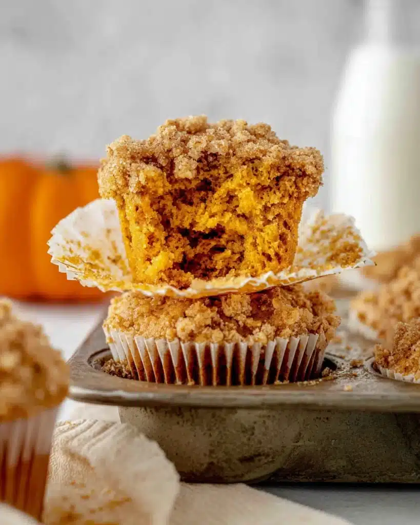 Close-up of a pumpkin oatmeal muffin with streusel topping and a bite taken out, showing moist interior.