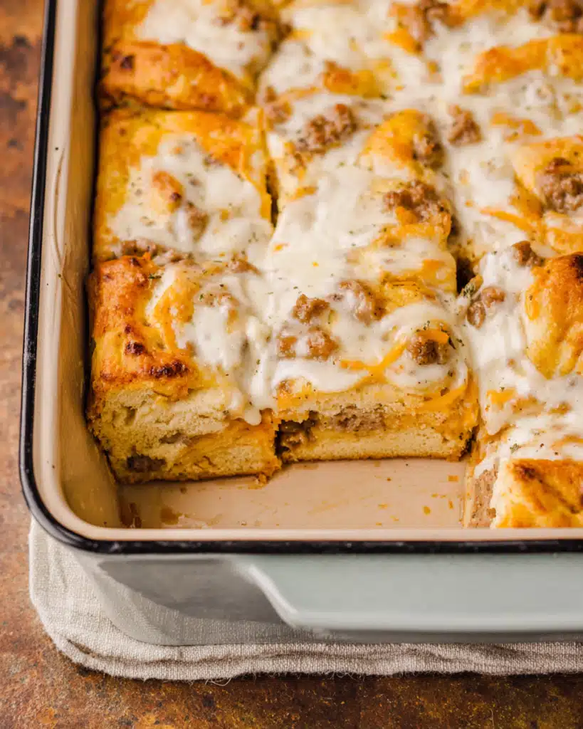 Close-up of baked biscuits and gravy casserole with golden edges and creamy gravy top
