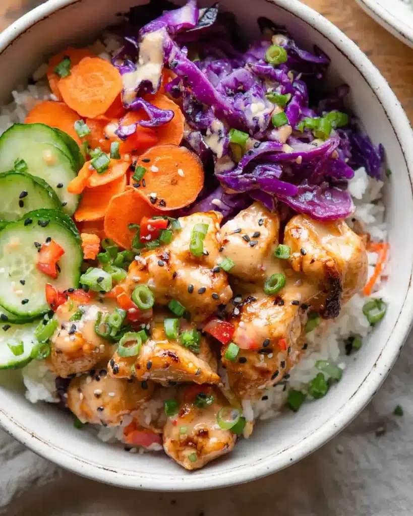 Close-up of Bang Bang Chicken Bowl with creamy sauce, sautéed veggies, and rice in white bowl