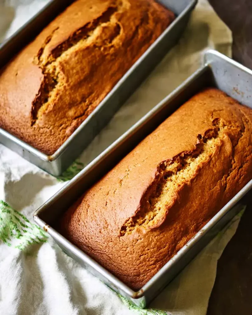 Freshly baked Easy Pumpkin Bread loaves cooling in metal pans