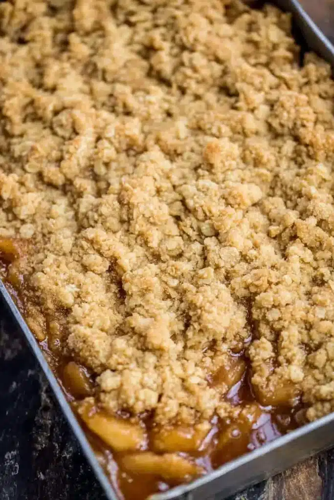 Close-up of baked apple crisp in metal pan with golden oat topping
