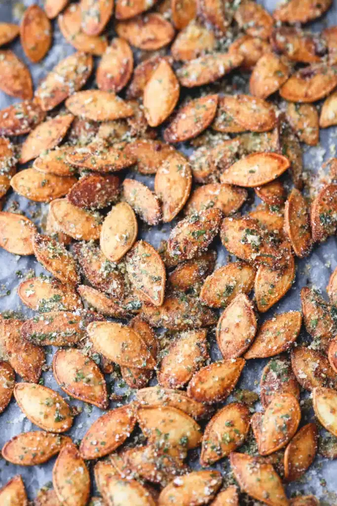 Roasted ranch pumpkin seeds scattered on a parchment-lined baking sheet, golden and seasoned