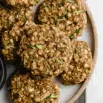 Soft chewy zucchini oatmeal cookies with visible oats and zucchini, stacked on a ceramic plate.