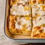 Biscuits and gravy breakfast casserole in a pan, with creamy gravy topping and golden biscuit layers