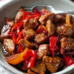 One pot black pepper chicken with red bell peppers in glossy sauce, served in a bowl with fork