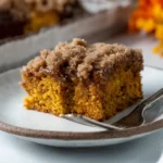 Moist pumpkin coffee cake slice with crumb topping on a white plate