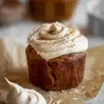 Pumpkin Dream Cupcakes with cinnamon espresso frosting and a swirl of extra frosting on parchment paper.