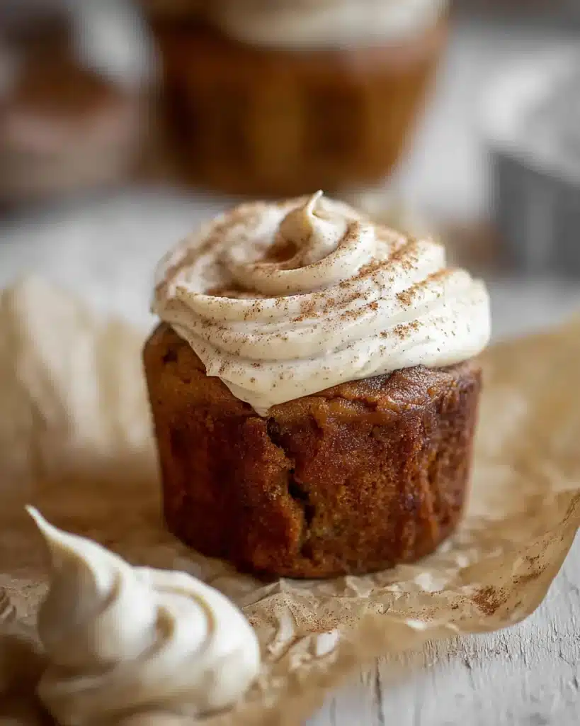 Pumpkin Dream Cupcakes with cinnamon espresso frosting and a swirl of extra frosting on parchment paper.