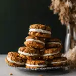 Stack of chewy pumpkin oatmeal cream pies with maple frosting on a vintage plate and warm fall background.