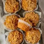 Freshly baked pumpkin oatmeal muffins topped with crunchy oat streusel in a parchment-lined tray.