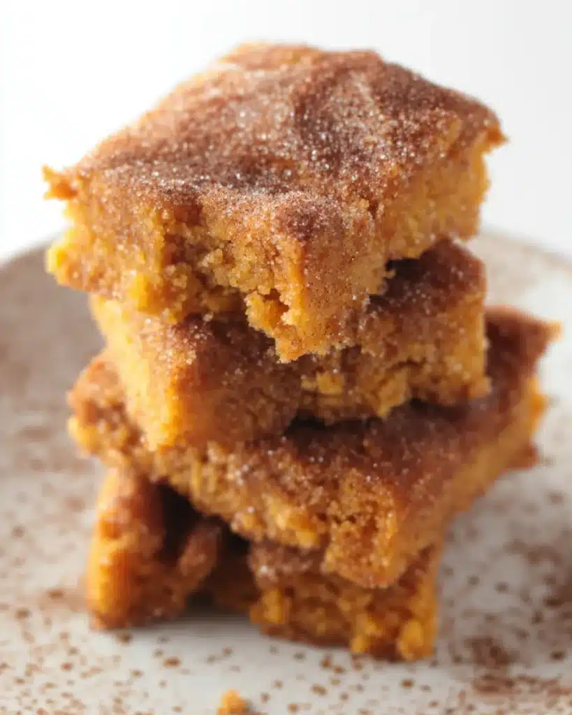 Stacked Pumpkin Snickerdoodle Snack Cake squares with a cinnamon sugar topping and soft golden interior