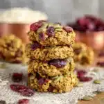 Stack of cookies from a Pumpkin Breakfast Cookies recipe, made with oats, seeds, and cranberries, on a rustic surface