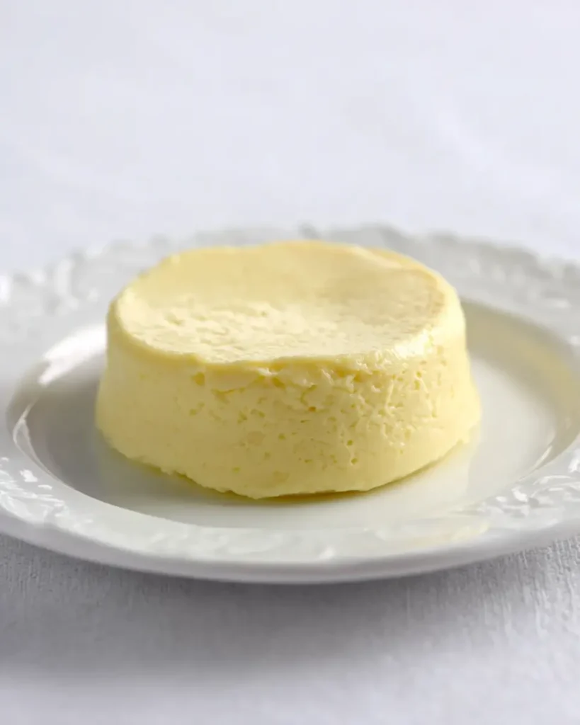 Plain keto cheesecake unmolded on a white plate with soft velvety top and creamy sides