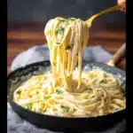 Side-by-side view of creamy lemon pasta before and after adding fresh herbs in black skillets