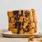 Stack of vegan pumpkin chocolate chip bread slices with melty chocolate on parchment paper