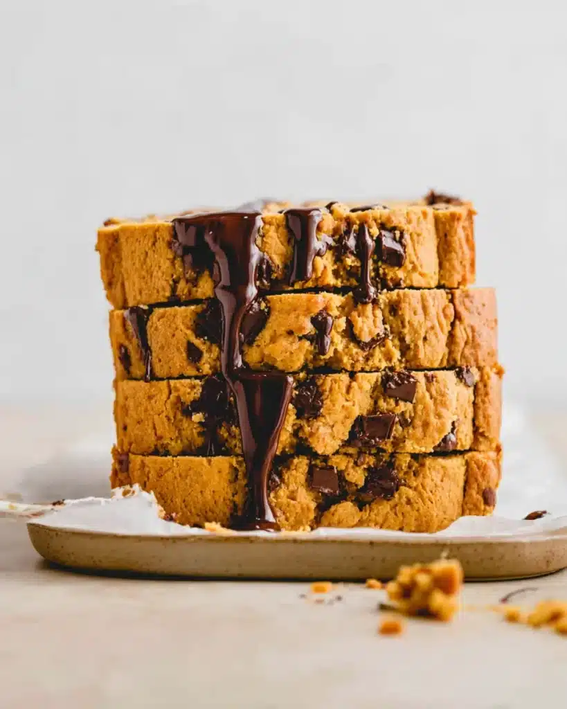 Stack of vegan pumpkin chocolate chip bread slices with melty chocolate on parchment paper