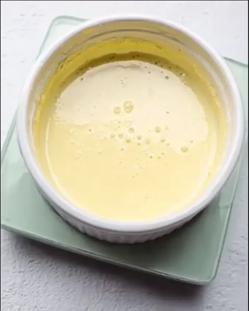 Smooth keto cheesecake batter in white ramekin resting on a digital kitchen scale