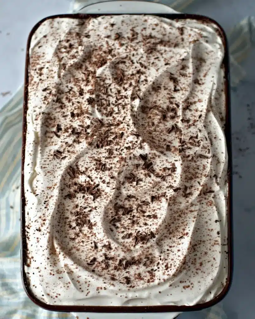 Overhead view of French Silk Brownies in ceramic baking dish topped with whipped cream and chocolate shavings.