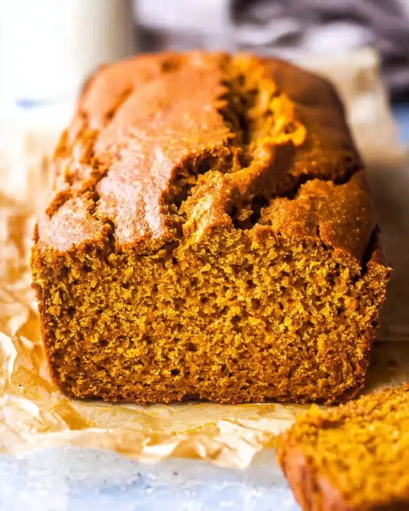 Whole loaf of vanilla pudding pumpkin bread with golden crust and moist pumpkin crumb on parchment