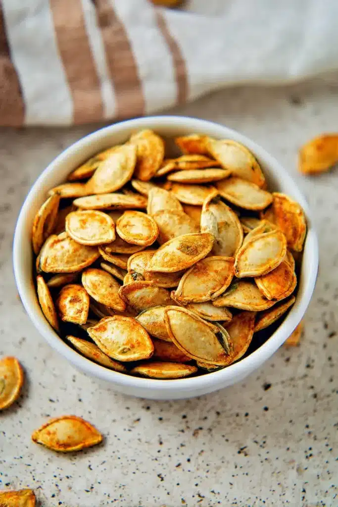 “Air Fryer Pumpkin Seeds in white bowl on cozy kitchen surface”