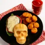Cheeseburger Skulls burger with melted cheese and tater tots on a plate, overhead Halloween photo