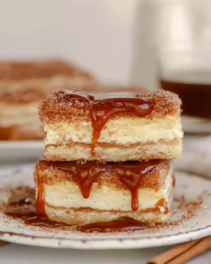 Churro cheesecake bars drizzled with caramel sauce on a plate