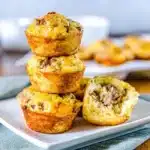Stack of golden brown sausage pancake bites on a white plate with a soft, fluffy interior and crispy edges.