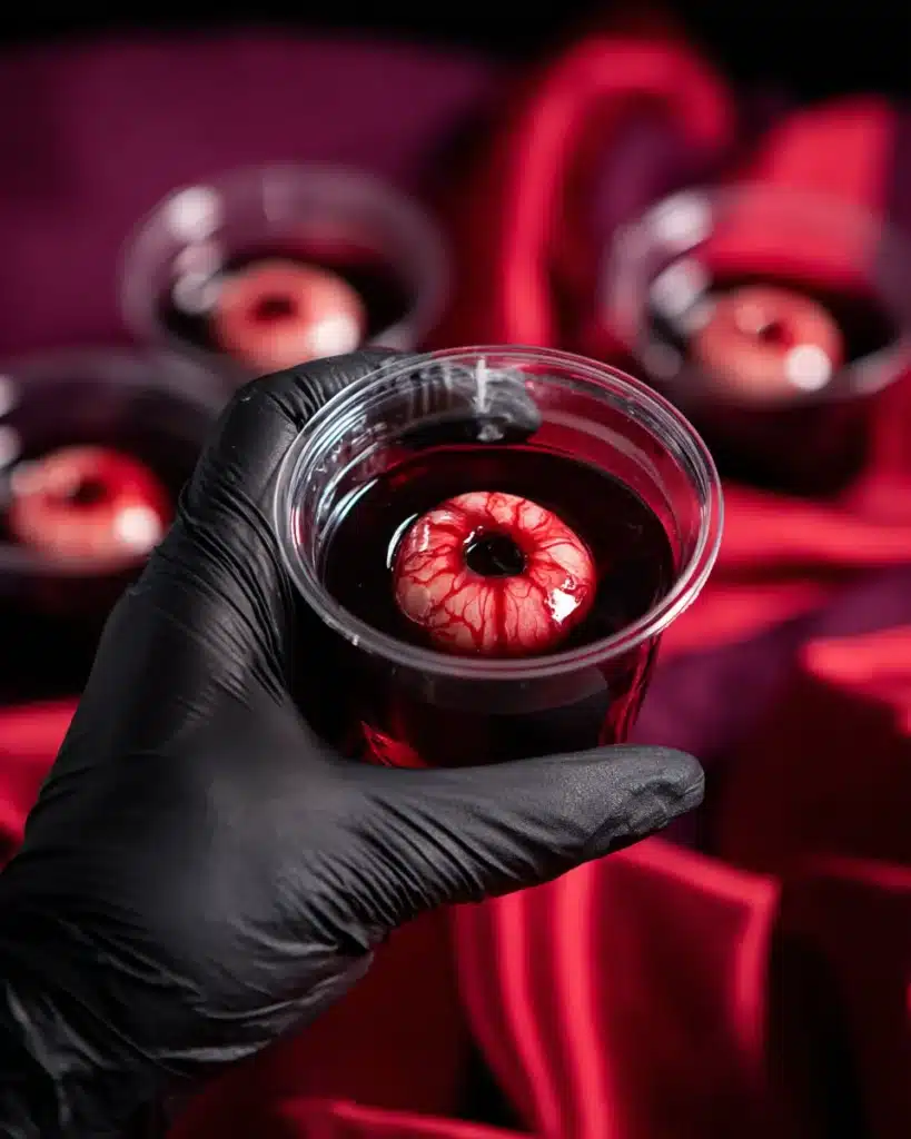 Hand holding eyeball jello shot in plastic cup for Halloween