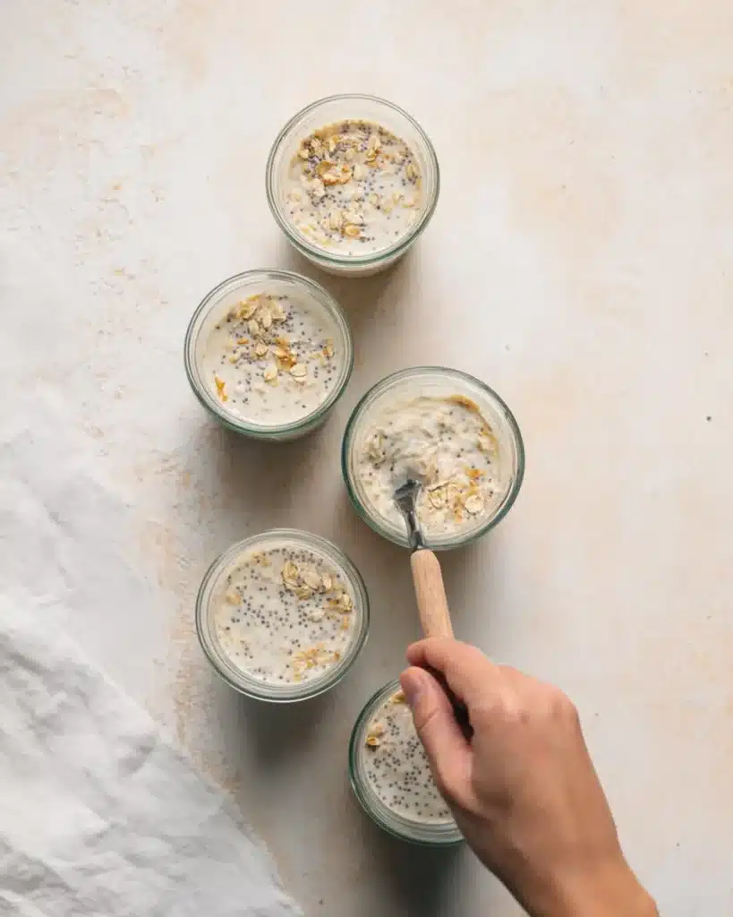 High-protein overnight oats mixture being stirred in glass jars