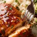 Juicy honey garlic chicken breast sliced with fork over rice