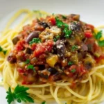 Spaghetti with Mediterranean eggplant pasta sauce topped with olives, parsley, and Parmesan