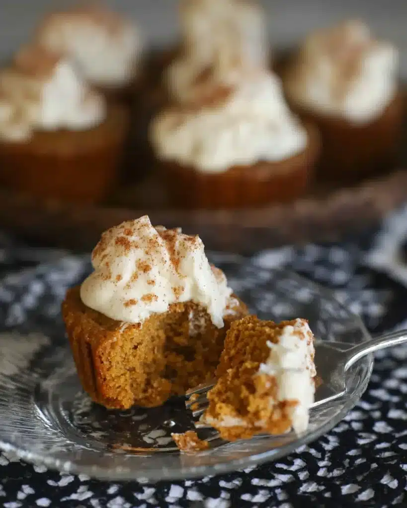 Close-up of pumpkin pie cupcake with whipped cream and bite on a fork showing soft interior
