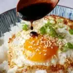 Sunny side up egg over steamed rice in a ceramic bowl – base layer of easy Korean egg rice