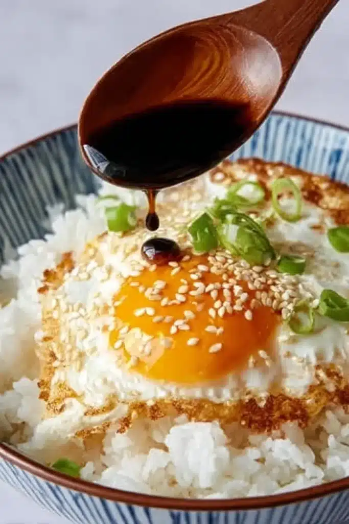 Sunny side up egg over steamed rice in a ceramic bowl – base layer of easy Korean egg rice