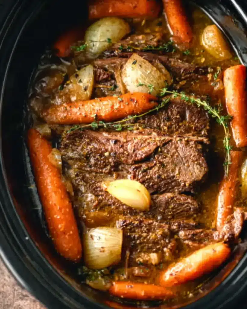 Slow cooker pot roast with carrots, onions, and broth in crockpot