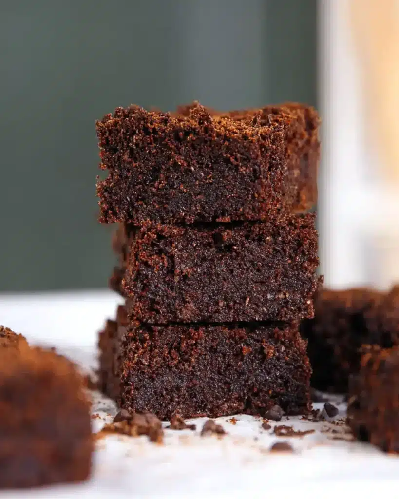 Stack of banana chocolate brownies with crumbly tops and chocolate chips on parchment paper