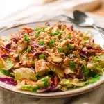 Whole30 Chinese Chicken Salad with creamy sesame dressing, fresh vegetables, and crunchy almonds on a white plate