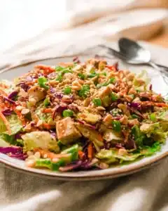 Whole30 Chinese Chicken Salad with creamy sesame dressing, fresh vegetables, and crunchy almonds on a white plate