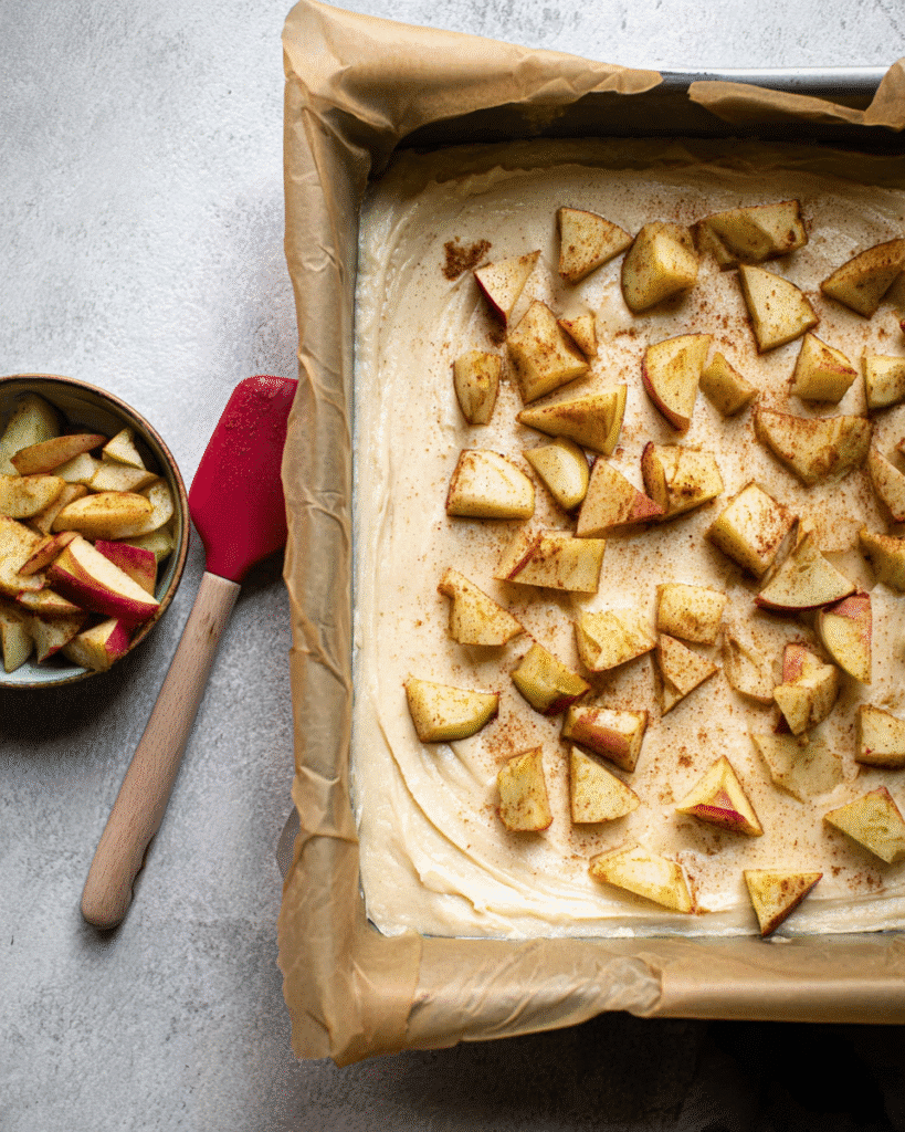 Apple crumb cake batter with cinnamon apples in baking pan