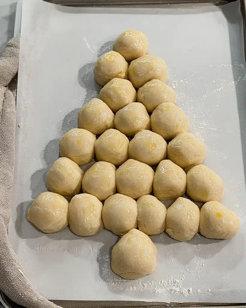 Unbaked dough balls arranged as a Christmas tree on baking sheet