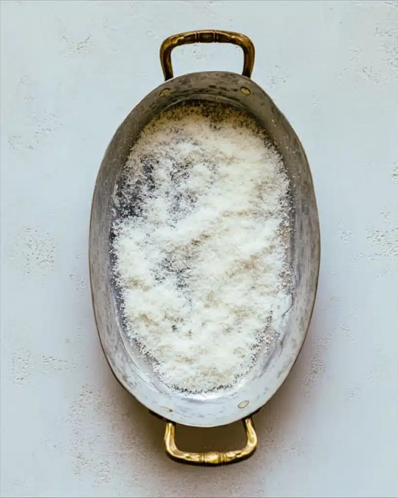 Butter-coated baking dish with Parmesan for cheesy root vegetable gratin