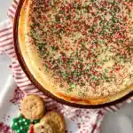 Overhead Christmas sugar cookie cheesecake with sprinkles and holiday cookies