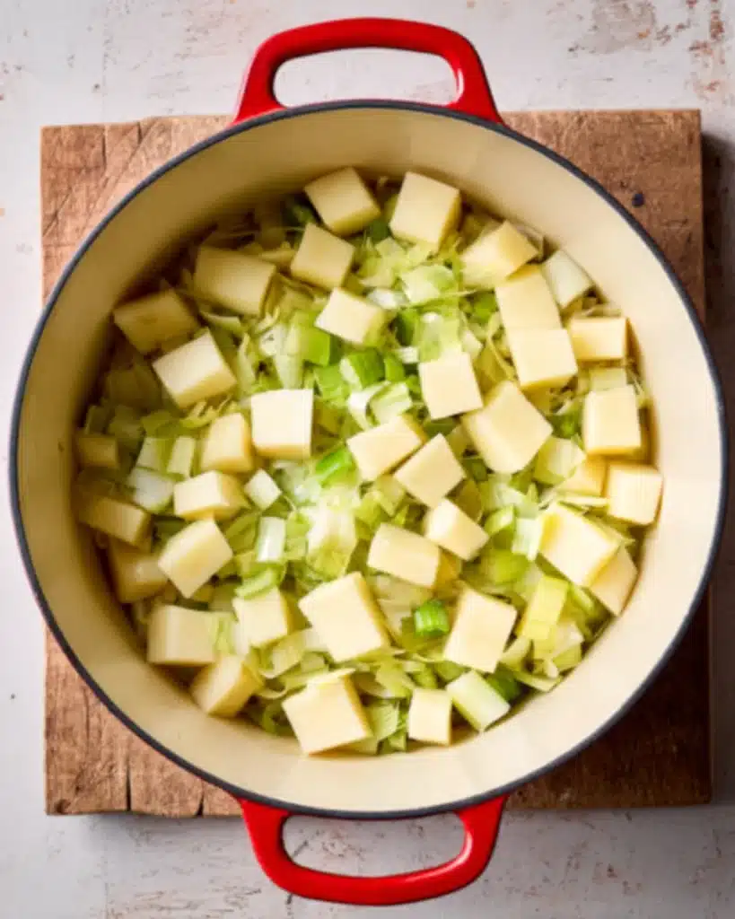 Cubed potatoes and leeks in Dutch oven for creamy leek and chicken soup
