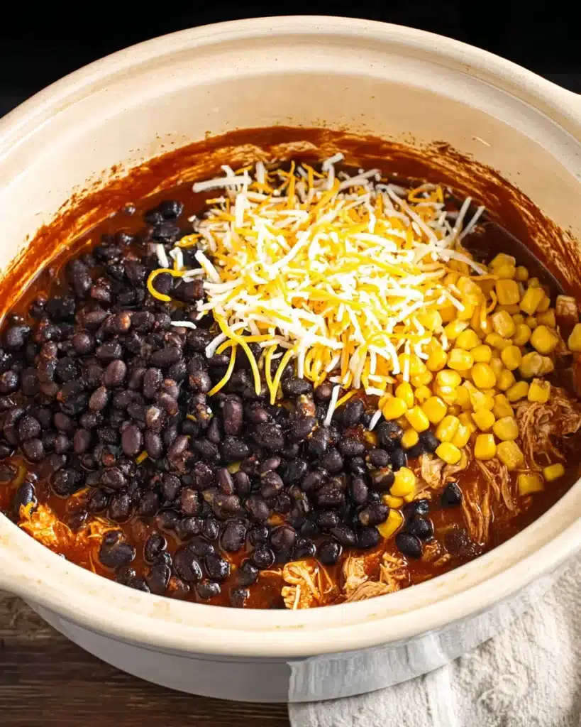 Crockpot chicken enchilada casserole with beans, corn, and cheese added