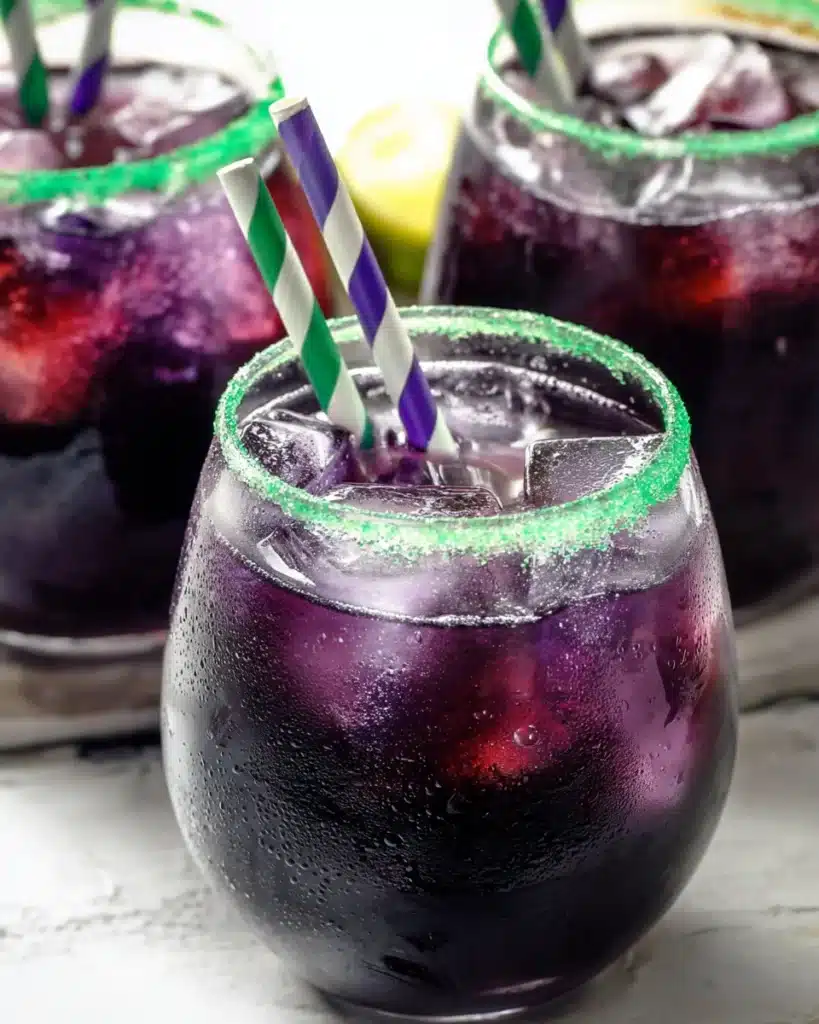 Drunk Witch Halloween cocktail with green sugar rim and striped paper straws