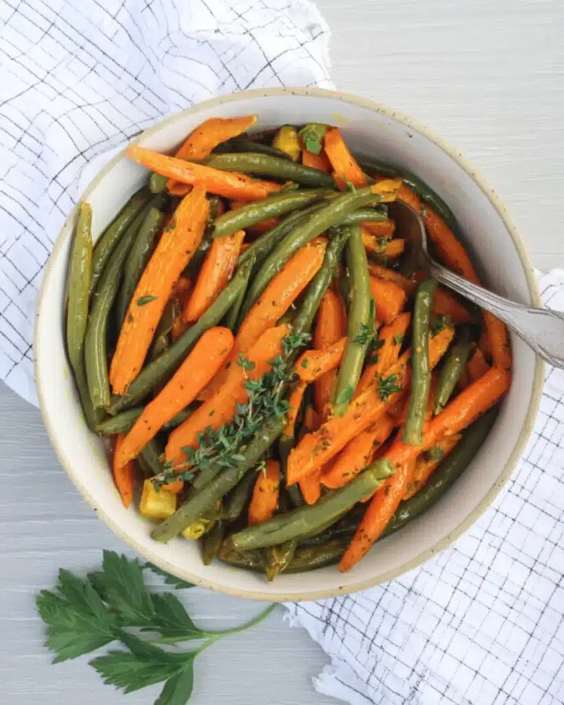 Top view of flavorful roasted carrots and green beans in serving bowl