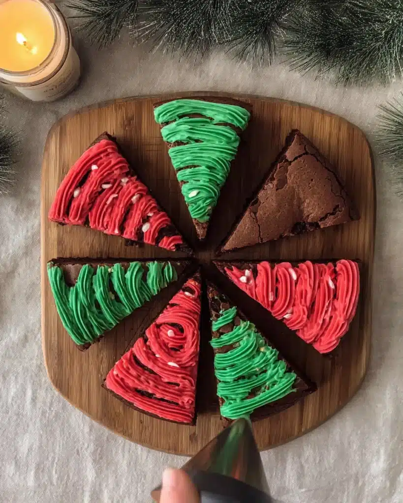 Decorating frosted Christmas brownies with red and green icing swirls