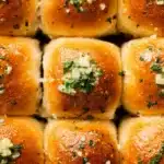 Golden garlic bread rolls topped with butter, garlic, and parsley