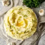 Creamy garlic mashed potatoes with melted butter and herbs in a rustic bowl